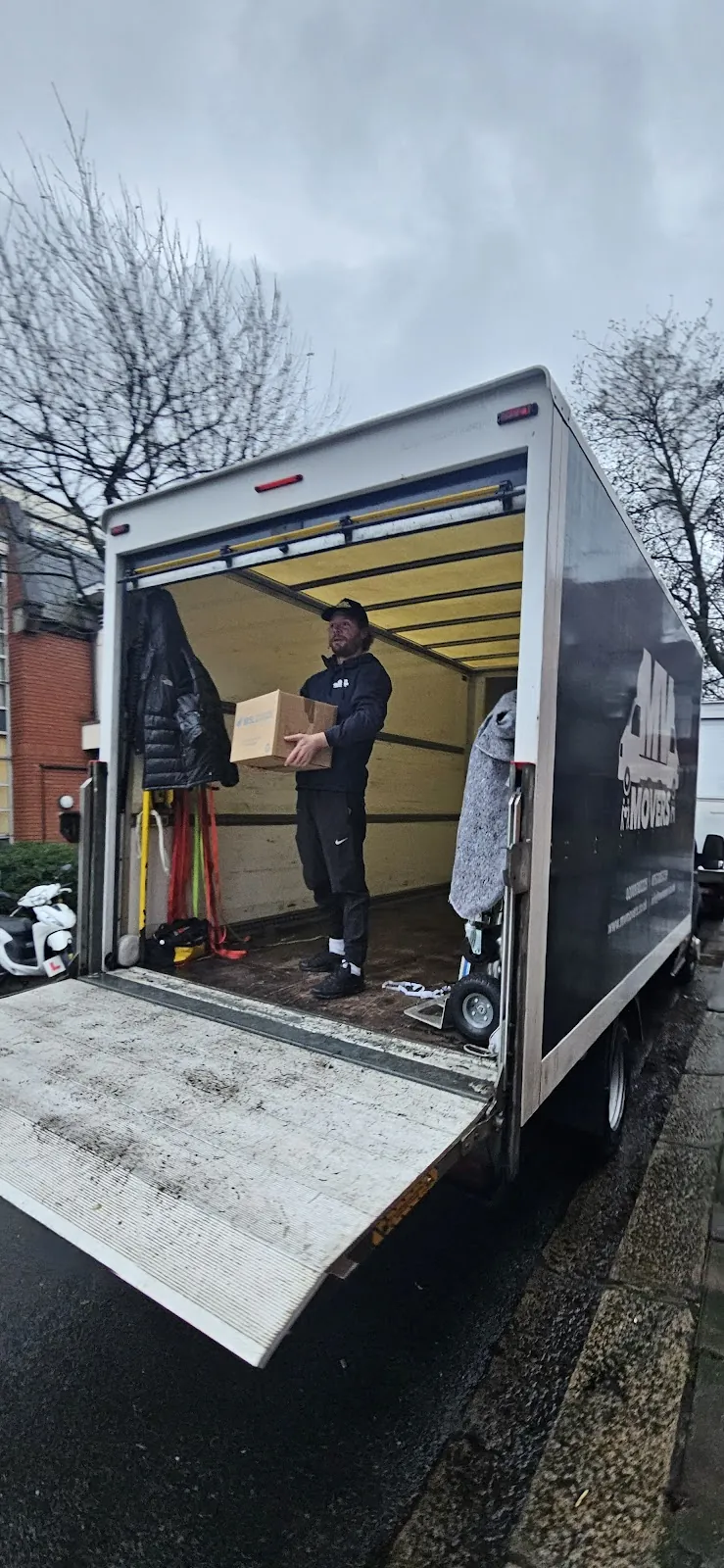 MV Movers crew loading boxes onto a Luton van tail-lift outside a rented property in West London